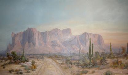 Superstition Mountain is the title of this painting by David Swing, depicting the iconic mountain with a foreground of a dirt road through desert landscape dotted by saguaros.