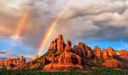 Amid falling rain from an isolated storm cell, a pair of rainbows appear over the sandstone buttes of Red Rock Country at sunset. In theory, all rainbows are double rainbows, but the secondary rainbow is often too faint to be seen. | Theresa Rose Ditson