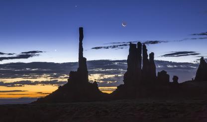 Dawn and night briefly share the sky over Ye Bi Chei at Monument Valley, in Northeastern Arizona. The Navajo people, on whose land this photograph was made, have strong spiritual beliefs tied to the moon. By Suzanne Mathia