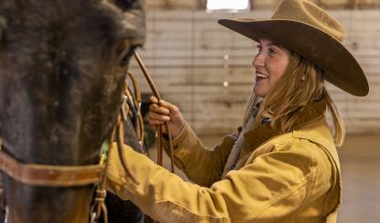 Grand Canyon wrangler Remy Kelbel prepares one of the mules at the South Rim for a morning ride. Kelbel is one of up to nine wranglers employed at the Canyon by Xanterra Travel Collection. By John Burcham