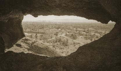 A hiker admires the view from Hole-in-the-Rock, the centerpiece of present-day Papago Park in Phoenix and Tempe, in an undated postcard photo. The site became Papago Saguaro National Monument in 1914, but it lost that designation less than two decades later. | Phoenix Public Library