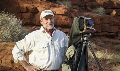 Portrait of Gary Ladd with 4x5 camera against a backdrop of red rocks is by Renee Roundtree.