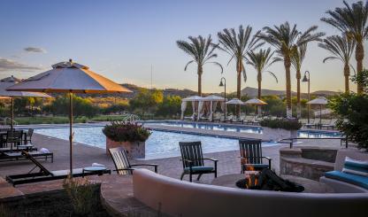 A calm swimming pool is shown, with lounge chairs and palm trees surrounding it. 