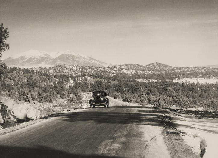 With the snowy San Francisco Peaks in the background, a motorist heads west on the stretch of Route 66 between Williams and Parks, likely in the 1930s or ’40s. | NORMAN G. WALLACE/ARIZONA HISTORICAL SOCIETY