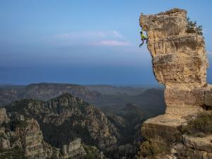 John Burcham captured this dramatic photo of a rock climber nearing the overhang at the top of rocky outcrop.