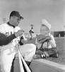 Baseball player wraps a bat as a child looks on.