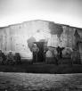 Cowboys stand in front of a ranch building in this black and white photograph