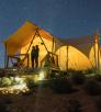 Campers look at a starry sky from beneath a canvas tent. 