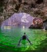 Diver in emerald-colored water inside a sea cave on the Colorado River. Photograph by Kerrick James.