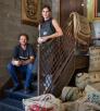 Daniel and Monica Garland pose with cups of coffee on a staircase near sacks of coffee beans. By David Zickl