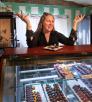Sarah Ann Lesslie behind a counter displaying fine chocolates at Chocolita.