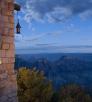The edge of a building appears in the left of an image that is dominated by the Grand Canyon under an evening sky. 
