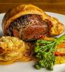 Beef Wellington with potato slices and vegetables fill a plate at Le Rendez-vous. By Steven Meckler