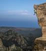John Burcham captured this dramatic photo of a rock climber nearing the overhang at the top of rocky outcrop.