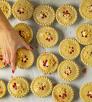 Photograph of a hand reaching for a small, decorative pie among dozens is by Steven Meckler