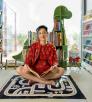 Cheron Taylor sits on a play rug in front of a bookshelf shaped like a dinosaur in the kid's section of Desierto Books in Tucson. | Steven Meckler