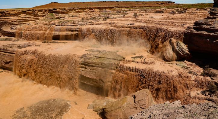 Muddy washes over the natural shelves of Grand Falls.