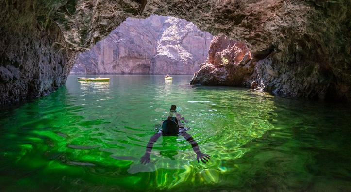 Diver in emerald-colored water inside a sea cave on the Colorado River. Photograph by Kerrick James.