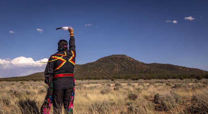 Stuart Chavez, a member of the Havasupai Tribe, raises an eagle feather toward Red Butte, one of the tribe’s sacred sites. By Eirini Pajak