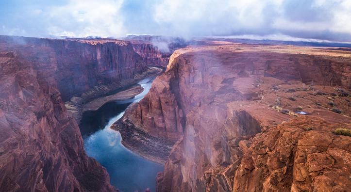 Fog and mist lift from Glen Canyon, revealing the sky reflected in the water below. By Gary Ladd