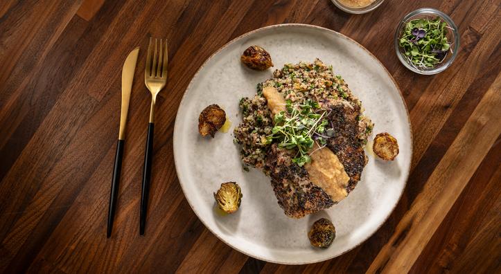 Herb crusted pork chops with sausage, apple, pecan and quinoa dressing, apple bourbon sauce and browned butter Brussels sprouts. By Rob Ballard