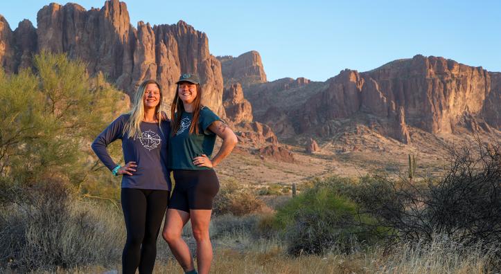 Lindsey Egan (left) and Melissa Wright pose in a desert setting with the Superstition Mountains in the background. By Shondiin Mayor