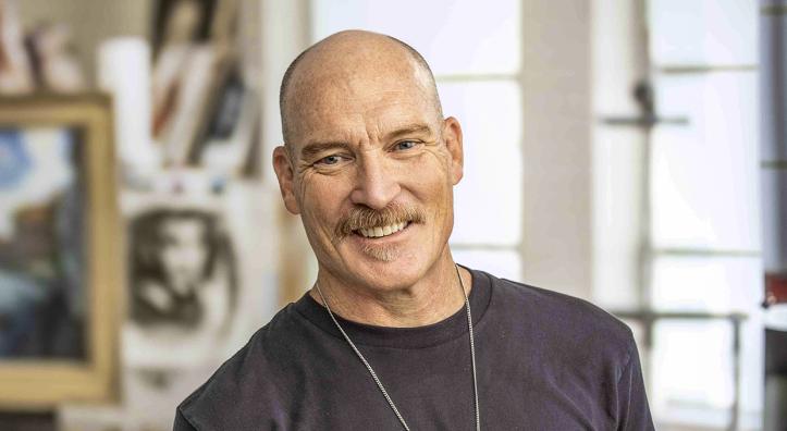 Photograph of Kevin Kibsey in studio setting holding a handful of paintbrushes is by Paul Markow.