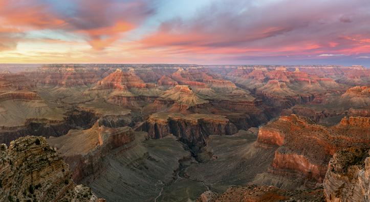 The setting sun colors the sky over the layered buttes of the Grand Canyon, as seen from the South Rim. Frequent visitors recommend arriving at the rim an hour before sundown to fully experience a sunset at the Canyon. By Adam Schallau