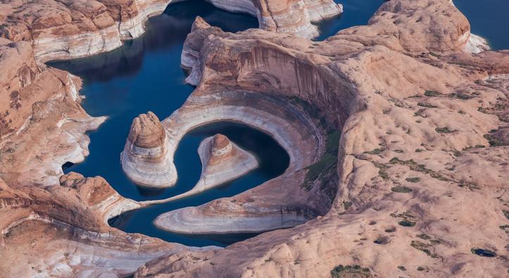 An aerial photo of Lake Powell’s Reflection Canyon displays the reservoir’s current and former water levels, along with the canyon’s looping course. By Gary Ladd