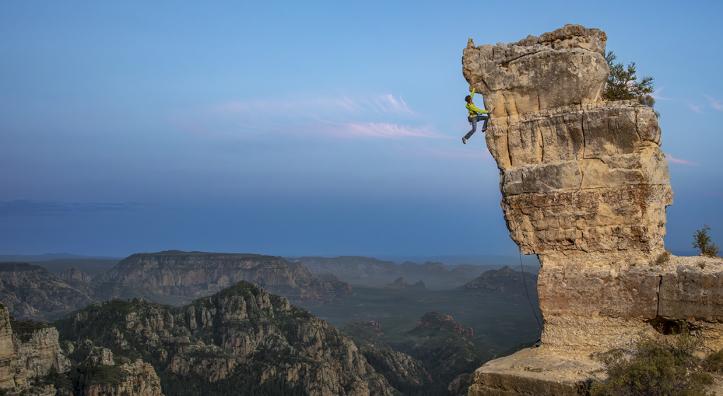 John Burcham captured this dramatic photo of a rock climber nearing the overhang at the top of rocky outcrop.