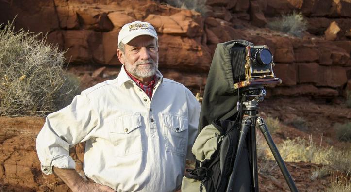 Portrait of Gary Ladd with 4x5 camera against a backdrop of red rocks is by Renee Roundtree.