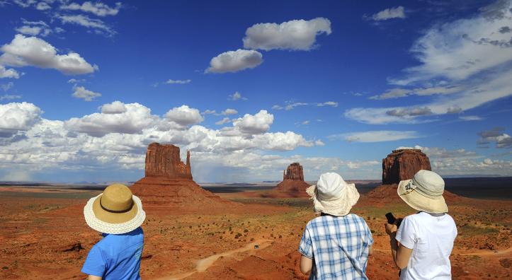 Three Japanese tourists take in a view of The Mittens in Monument Valley. By Marie Baronnet