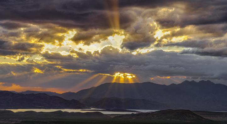 Rays of sunlight burst through dark and gloomy storm clouds at Parker Canyon. | Claire Curran