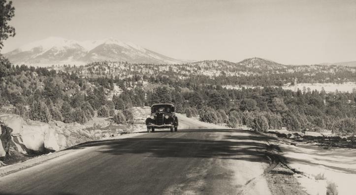 With the snowy San Francisco Peaks in the background, a motorist heads west on the stretch of Route 66 between Williams and Parks, likely in the 1930s or ’40s. | NORMAN G. WALLACE/ARIZONA HISTORICAL SOCIETY
