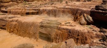 Muddy washes over the natural shelves of Grand Falls.