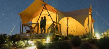 Campers look at a starry sky from beneath a canvas tent. 