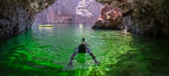 Diver in emerald-colored water inside a sea cave on the Colorado River. Photograph by Kerrick James.
