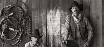 Black and white photo of cowboys Buster Scarbrough and Bob Pulley pose for a photo at the A Bar V Ranch in Skull Valley in 1981. This shot was one of several Jay Dusard photos published in the August 1982 issue of Arizona Highways. 