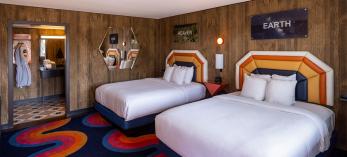 A room at the Americana Motor Hotel features a cheery mashup of bright yellows, oranges and blues with faux wood paneling that captures the flavor of a bygone era. By John Burcham