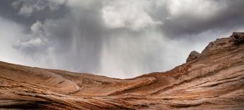 A sudden spring storm looms over the sandstone formations of White Pocket, part of Vermilion Cliffs National Monument north of the Grand Canyon. By Suzanne Mathia