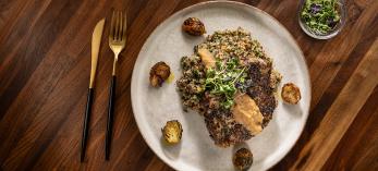 Herb crusted pork chops with sausage, apple, pecan and quinoa dressing, apple bourbon sauce and browned butter Brussels sprouts. By Rob Ballard