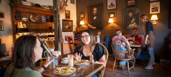 People dining at wooden tables and chairs inside the Bear & Dragon Café. By Dan Kish