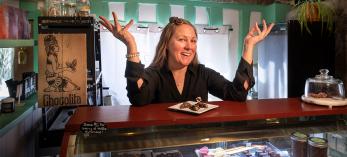 Sarah Ann Lesslie behind a counter displaying fine chocolates at Chocolita.