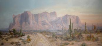 Superstition Mountain is the title of this painting by David Swing, depicting the iconic mountain with a foreground of a dirt road through desert landscape dotted by saguaros.