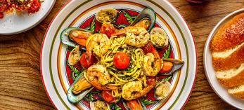 Bowl of pasta with tomatoes and seafood with meatballs in red sauce, bread and red wine. By Steven Meckler