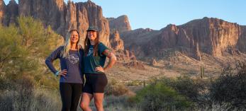 Lindsey Egan (left) and Melissa Wright pose in a desert setting with the Superstition Mountains in the background. By Shondiin Mayor