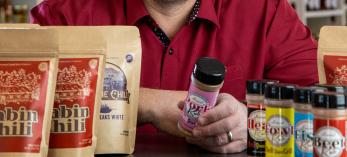 Jeremy Cox in a store setting with a selection of his chili mixes and rubs. By Paul Markow