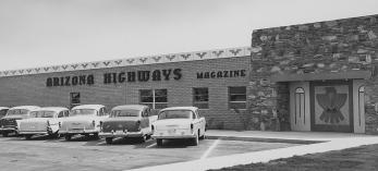 Black and white photo of Phoenix building that is home to Arizona Highways magazine, with mid-century automobiles parked in the front lot. | Arizona Highways Archives