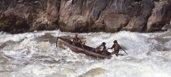 Bruce Simballa (on oars) and Kenton Grua (steering) guide an authentic Whitehall boat, the kind used by John Wesley Powell’s party, through the Grand Canyon’s Granite Rapids for an Imax film in 1984. Powell’s group portaged these rapids, but modern boatmen have the skills and experience to run these boats through the Canyon’s largest rapids. By Rudi Petschek