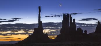 Dawn and night briefly share the sky over Ye Bi Chei at Monument Valley, in Northeastern Arizona. The Navajo people, on whose land this photograph was made, have strong spiritual beliefs tied to the moon. By Suzanne Mathia